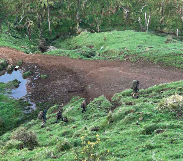 Still image from video taken by pig hunters of Tom Phillips and the children on 3 October 2024 with the four figures walking across a hillside.